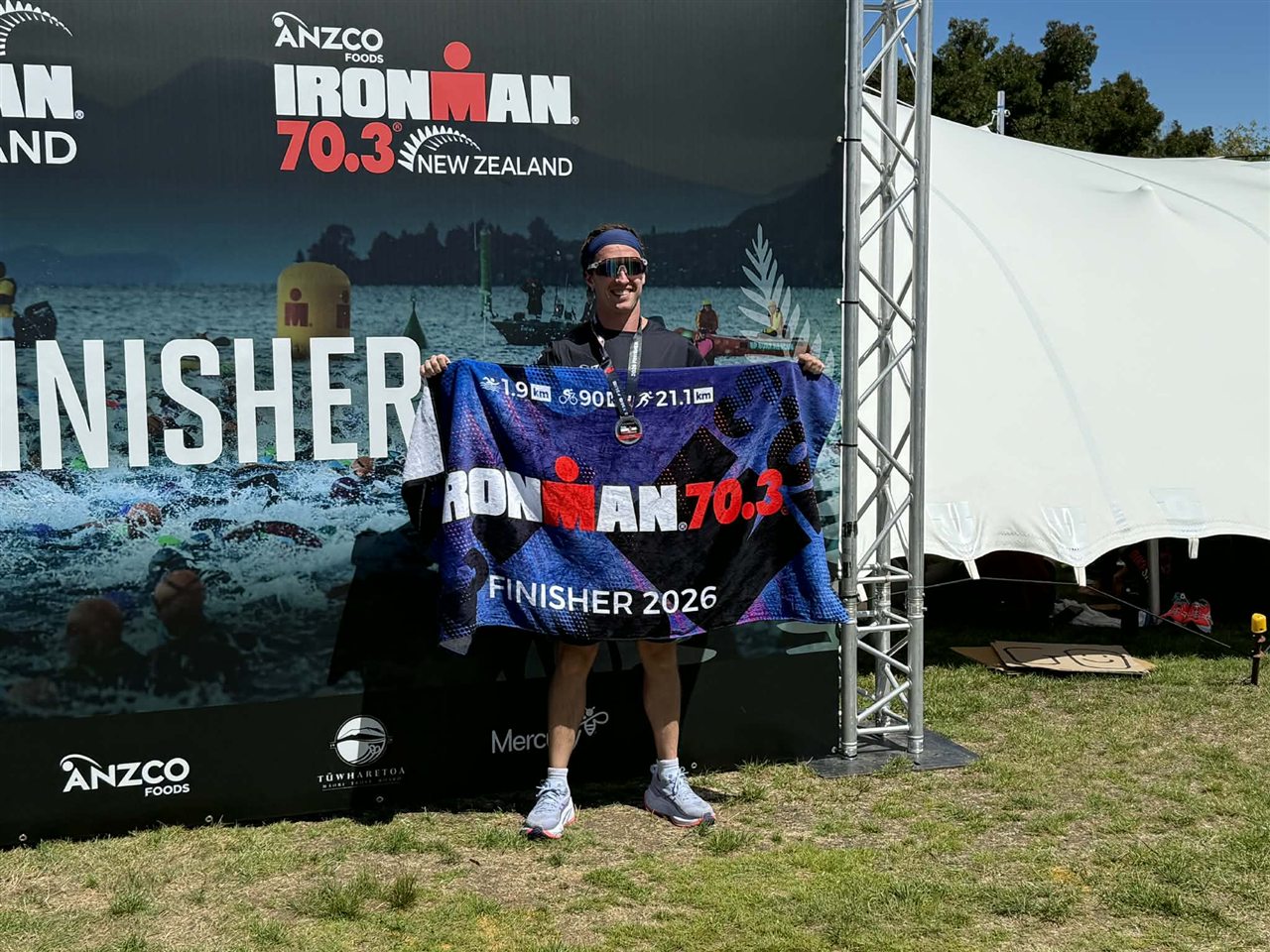 Tristen Oosthuizen holding an Ironman 70.3 finisher banner